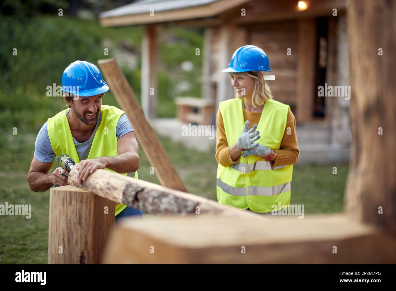 I costruttori stanno chiacchierando mentre lavorano su un cottage di legno nella foresta in una bella giornata. Costruzione, costruzione, lavoratori Foto Stock