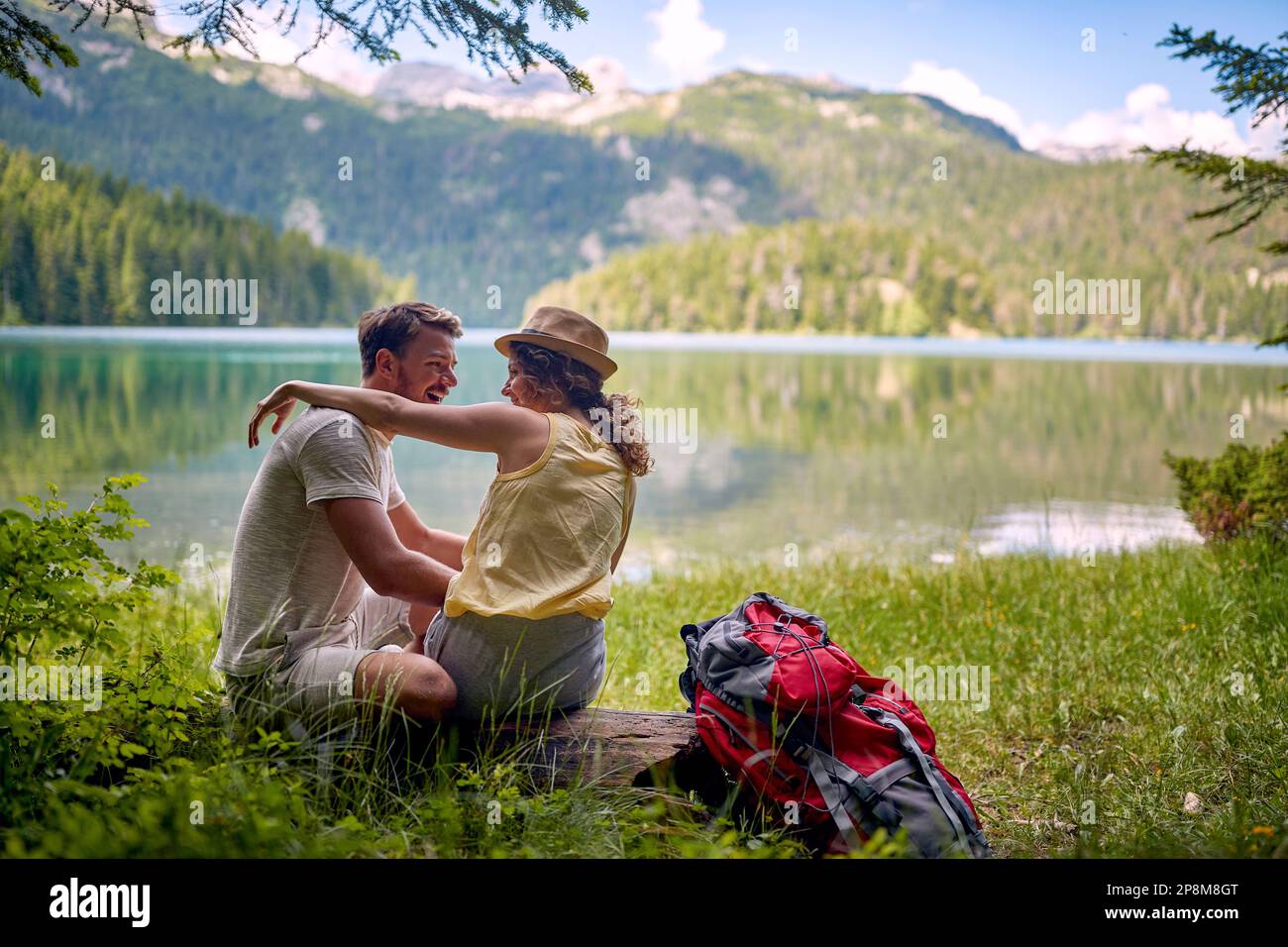 giovane coppia caucasica che si abbraccia a vicenda sul lago con una bella vista di fronte a loro Foto Stock