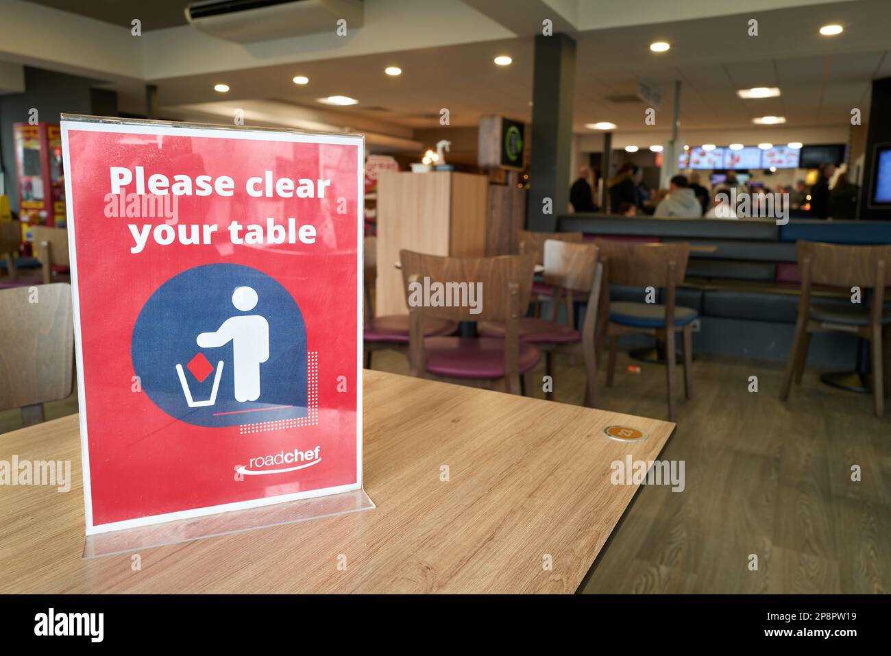 Avviso "si prega di cancellare il vostro tavolo" su un tavolo al MacDonald's café in un'area di servizio sulla strada A1, Inghilterra. Foto Stock