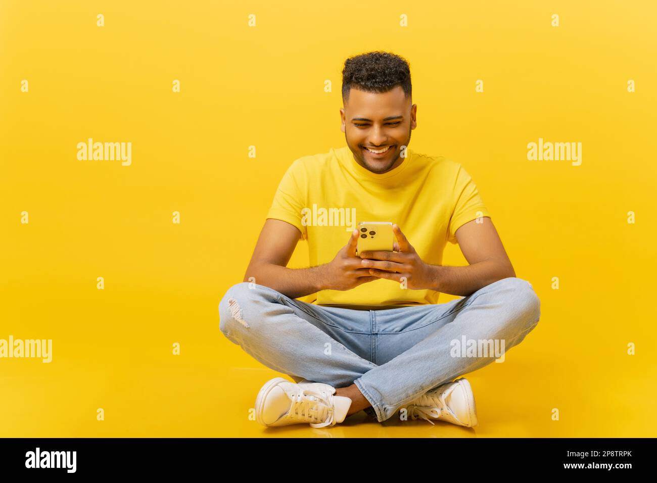 Addicted alla messaggistica sorridente giovane indiano 20s uomo con  smartphone in mano seduto in lotus posa isolato su giallo. Bell'ottimista  che usa l'app mobile, chattare online, giocare Foto stock - Alamy