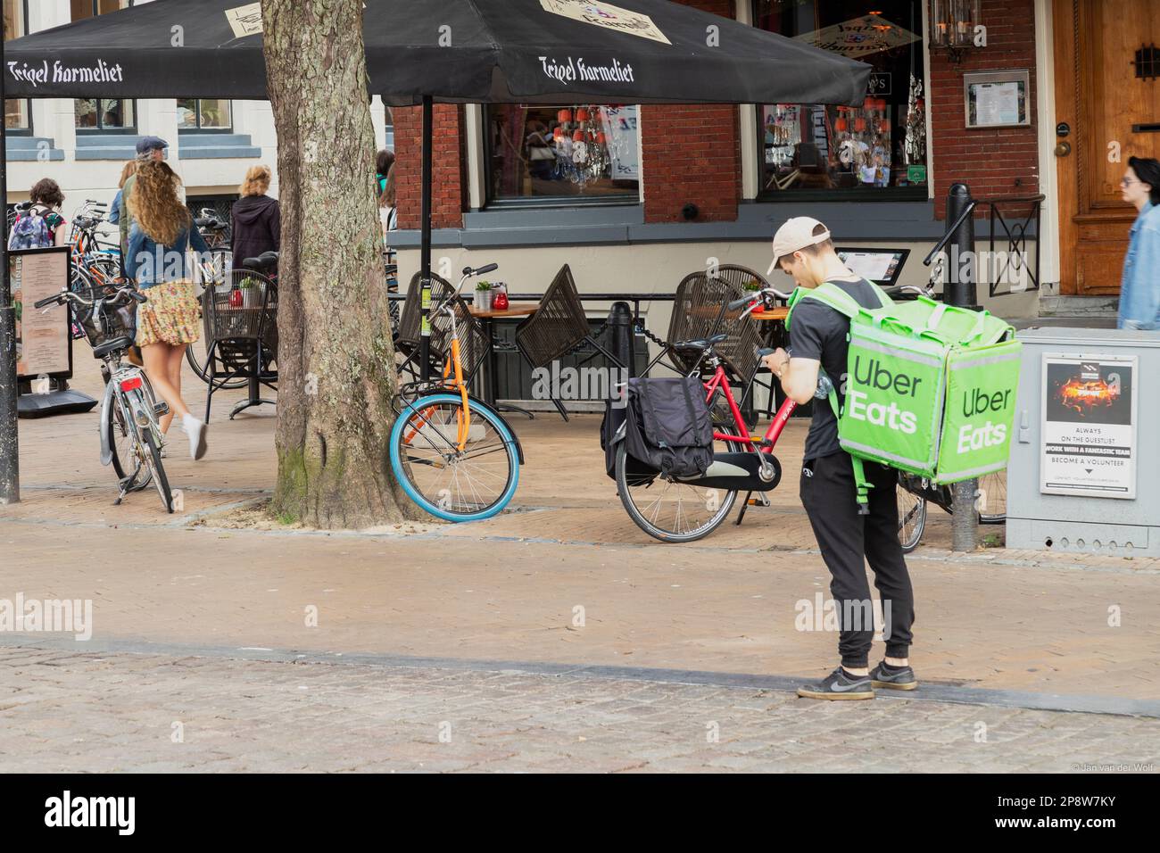 Un ragazzo con un Uber mangia una borsa cerca la sua strada sul suo cellulare nella città olandese di Groningen Foto Stock