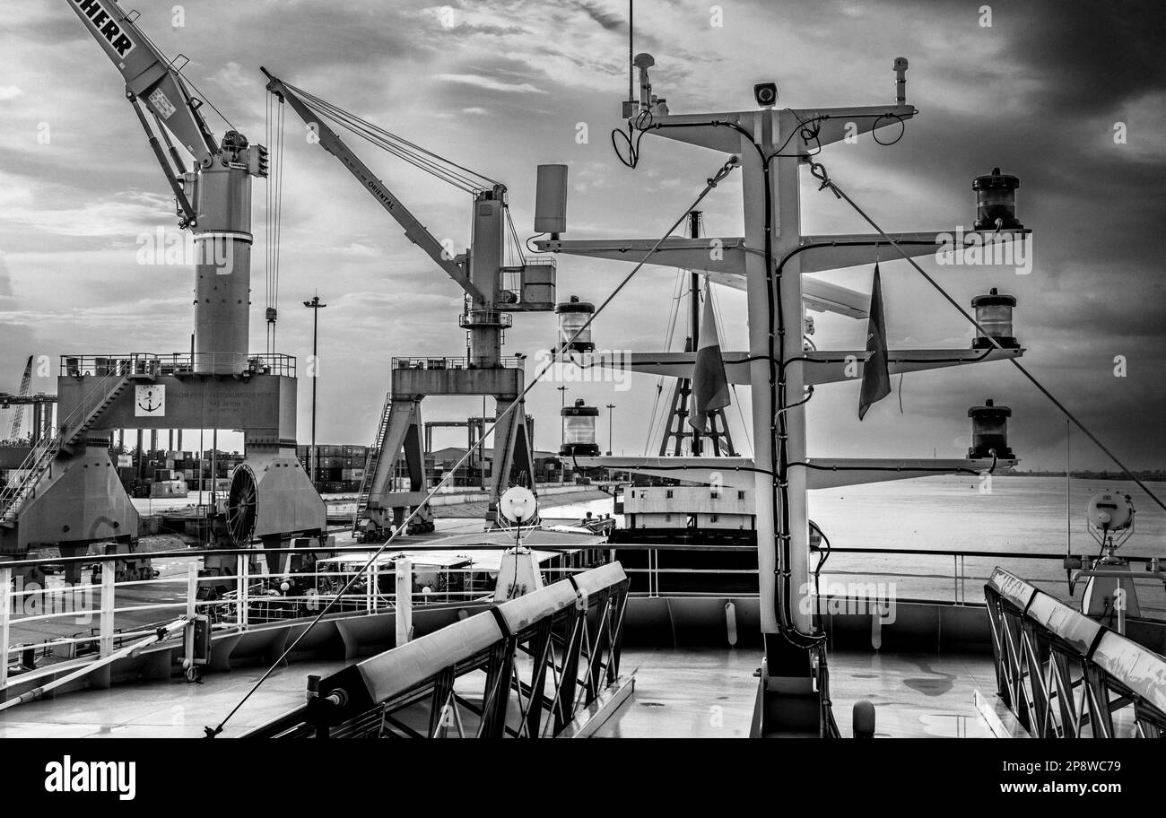 L'albero di una nave da crociera fluviale vicino a gru di grandi dimensioni sulla banchina al porto container a Phnom Penh, Cambogia. Foto Stock