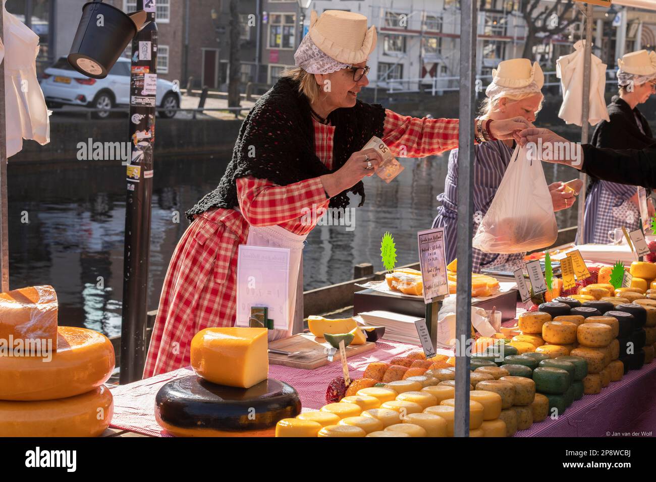 Venditori di formaggio femminile con abbigliamento tradizionale in una bancarella del mercato del formaggio Alkmaar nei Paesi Bassi. Foto Stock