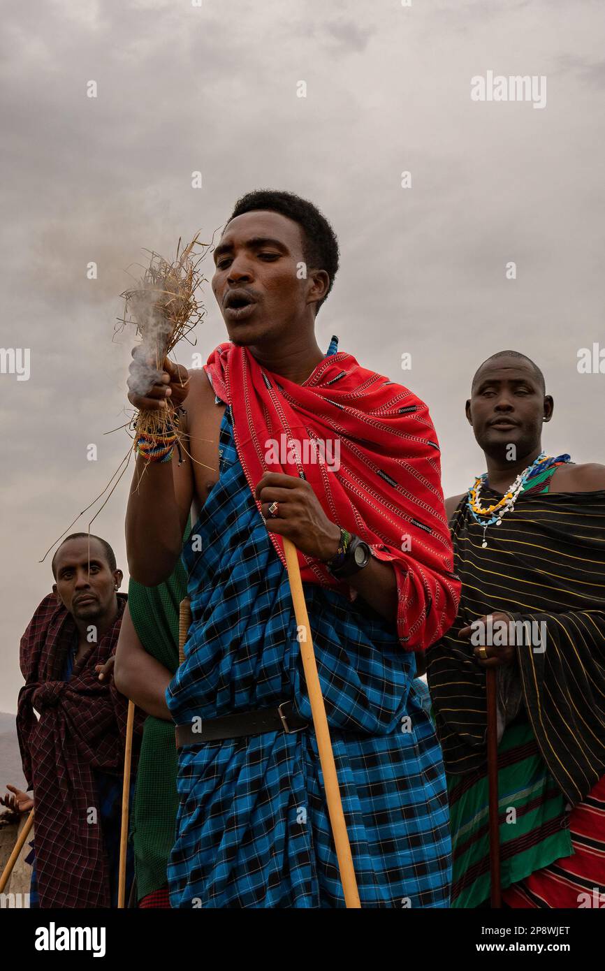 Karatu, Tanzania - 16th ottobre 2022: Un uomo masai che dimostra una tecnica tradizionale di illuminazione del fuoco, soffiando su erba secca dopo che ha preso fuoco. Foto Stock