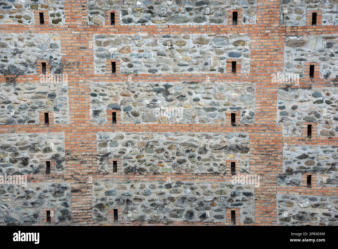 Detalle de un antiguo muro hecho medievale con piedras, ladrillos y otros materiales, textura Foto Stock