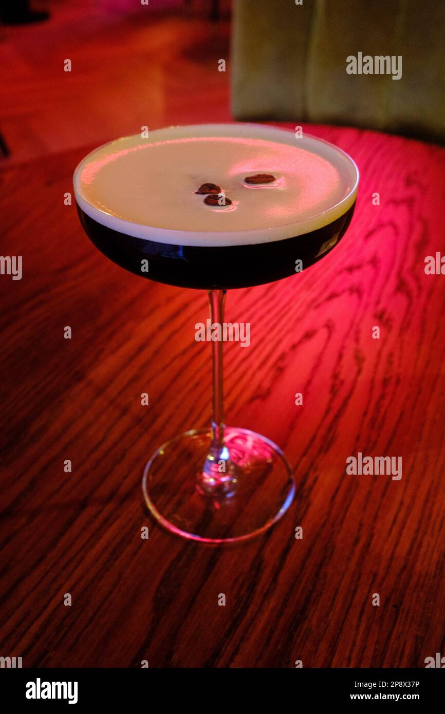 Cocktail russo nero in un classico cocktail bar su un tavolo da bar con luce rossa sullo sfondo Foto Stock