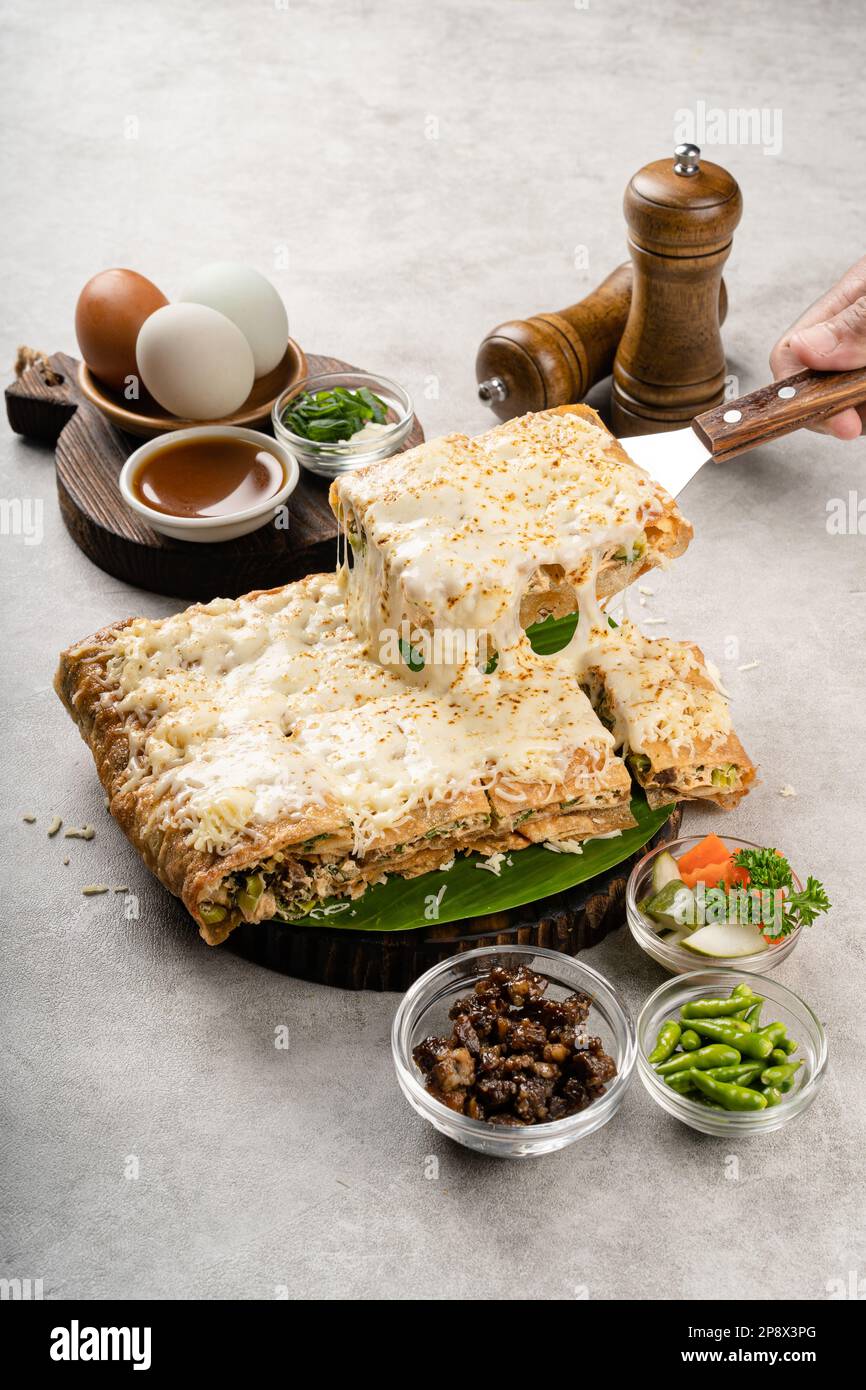Martabak telur è cibo di strada indonesiano, fatto con saporita pasta fritta in padella farcita con uova, cipollina, carne, salsiccia, spezie e formaggio. Foto Stock