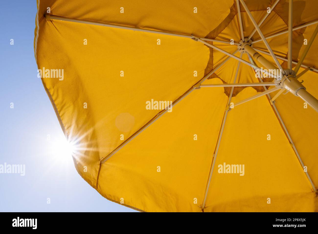 La protezione dal sole in un resort estivo. Ombrello giallo blu su sfondo cielo Foto Stock