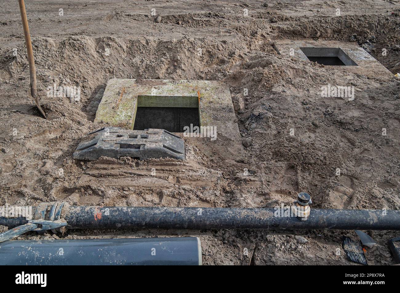 terreno edificabile in sabbia con due pozzi di cemento e tubi di plastica Foto Stock