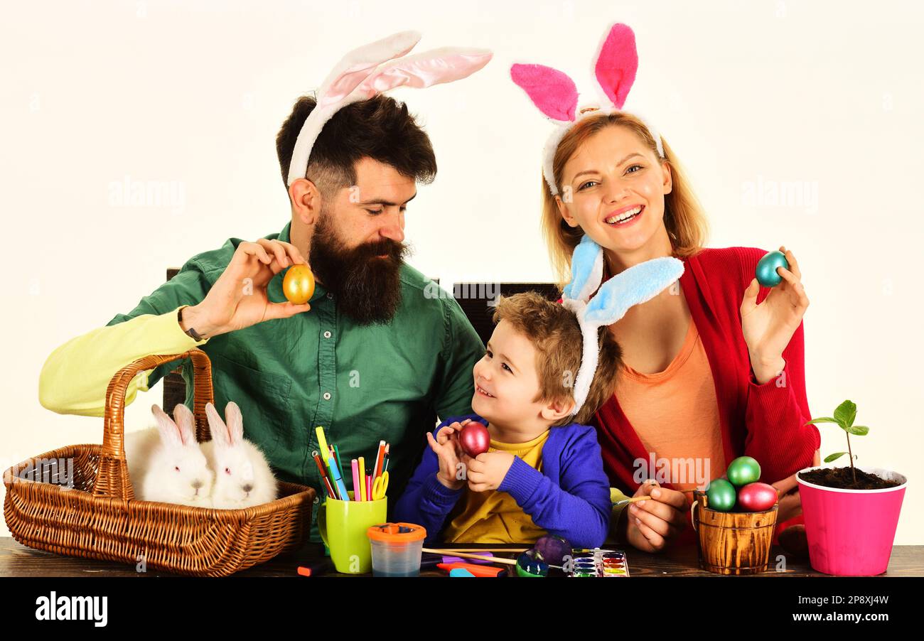 Tradizioni di famiglia di Pasqua. Caccia alle uova. Madre, padre e figlio si preparano per le vacanze di Pasqua. Genitori felici e adorabile ragazzo in orecchie coniglietto con colorato Foto Stock