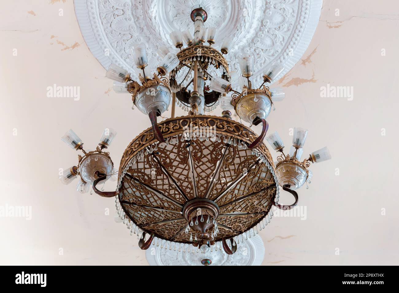Lampadario in cristallo d'ottone d'epoca in stile antico a Niko Berdzenishvili Kutaisi state History Museum, sala espositiva principale, ornamenti in gesso sul soffitto. Foto Stock