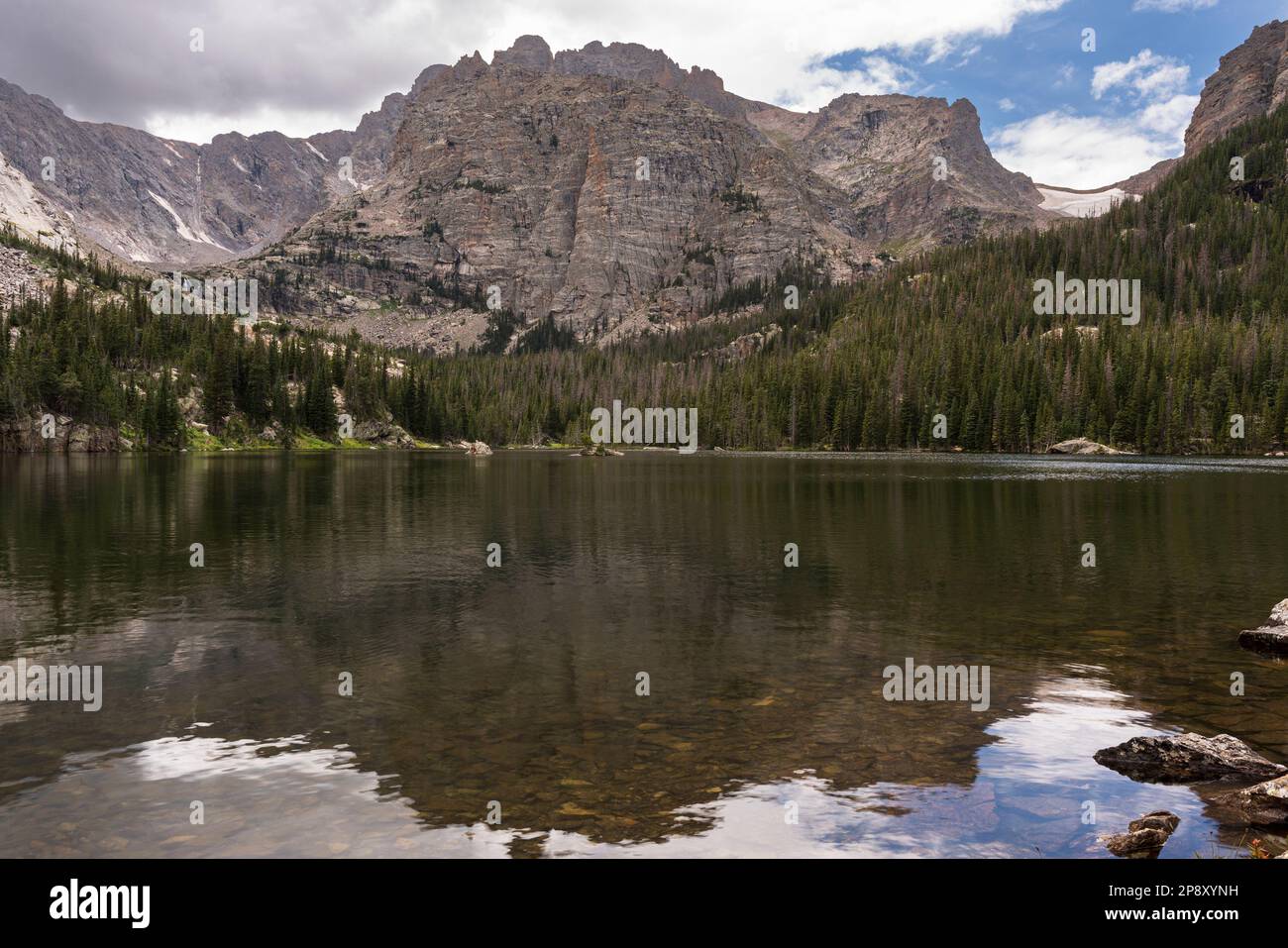 Le vette delle Montagne Rocciose si riflettono in una parte del lago Loch, una meta popolare per gli escursionisti per il suo splendido paesaggio presso il Rocky Mountain National Foto Stock
