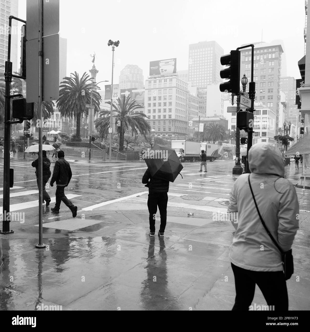 Pedoni e turisti sotto la pioggia nel centro di San Francisco, California; persone in condizioni di pioggia e tempo umido in visita sul marciapiede e strada Foto Stock