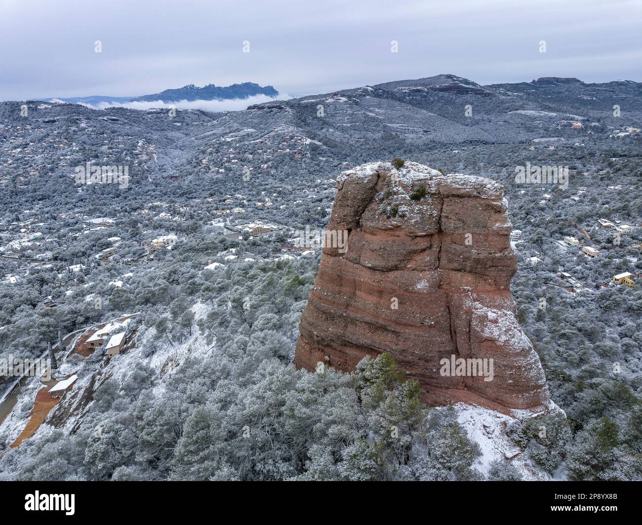 Veduta aerea del nevoso Cavall Bernat della roccia di Matadepera, a la Mola, dopo una nevicata nel 02-27-2023. Sullo sfondo, Montserrat, Catalogna, Spagna Foto Stock