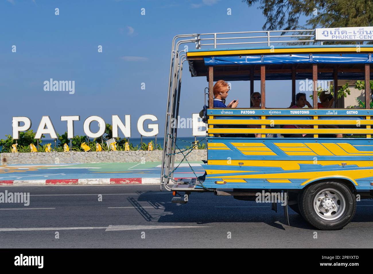 Un songthaew (tipo di autobus locale) guida oltre il punto di riferimento 'Phuket Beach' che si trova sulla strada della spiaggia di Patong (Thaweewong Rd.), Patong, Phuket, Thailandia Foto Stock