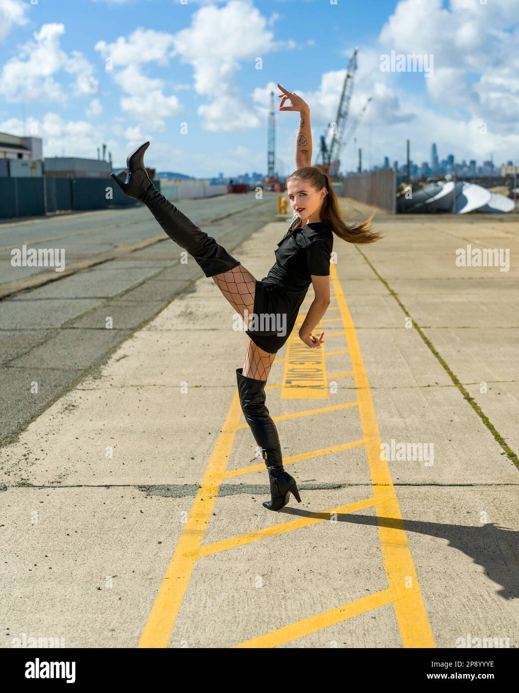 Bella giovane donna fare Kick Step mentre attraversa la strada | Dance Move | Goth Style Foto Stock