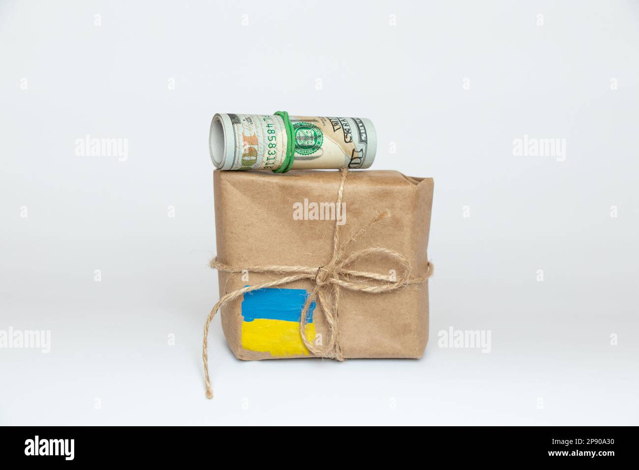 Scatola marrone con una bandiera dipinta dell'Ucraina e cento dollari su sfondo bianco, aiuto umanitario per l'Ucraina 2023 Foto Stock