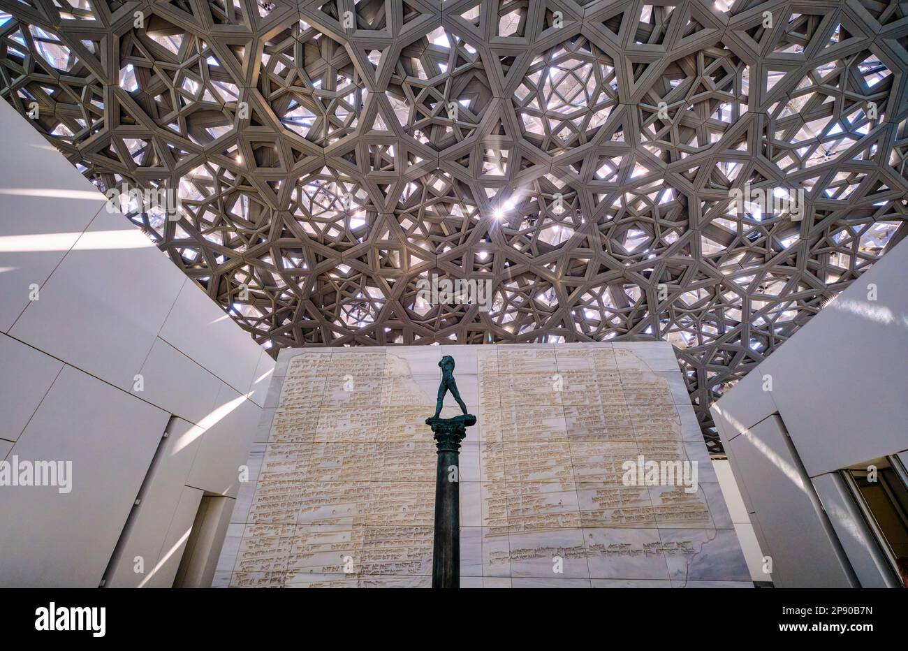 Una statua senza testa di un uomo con il metallo grigio, acciaio tessuto griglia aperta del lato inferiore della grande cupola che copre il museo. Al Louvre francese Foto Stock
