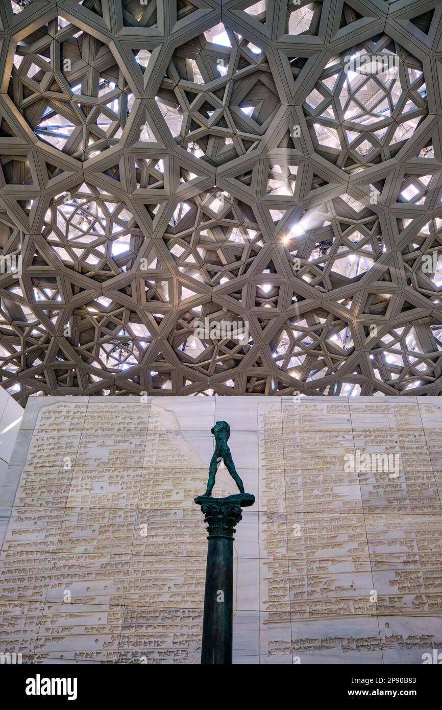 Una statua senza testa di un uomo con il metallo grigio, acciaio tessuto griglia aperta del lato inferiore della grande cupola che copre il museo. Al Louvre francese Foto Stock