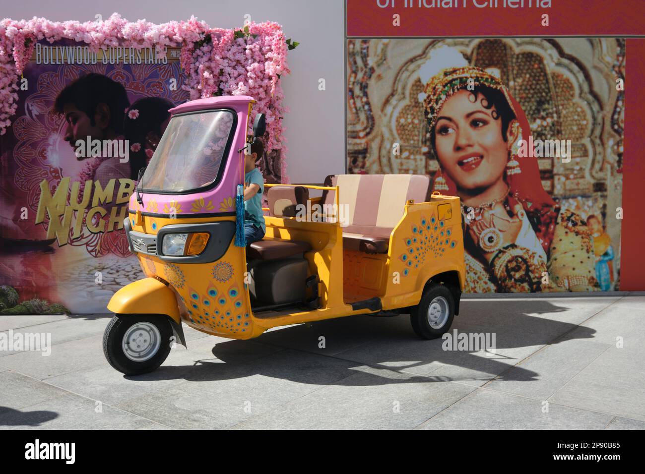 Un carino risciò giallo e rosa auto, tuk tuk, parte di uno spettacolo temporaneo sulla storia del cinema indiano, film, film. Al museo d'arte del Louvre francese Foto Stock