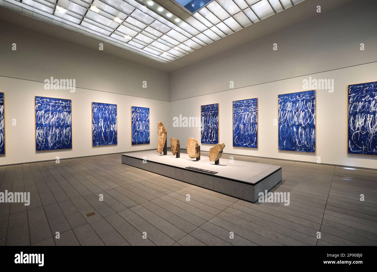 Una sala galleria dedicata a un insieme di dipinti blu moderni e una pietra, scultura installazione. Al museo d'arte francese del Louvre ad Abu Dhabi, negli Emirati Arabi Uniti, Foto Stock