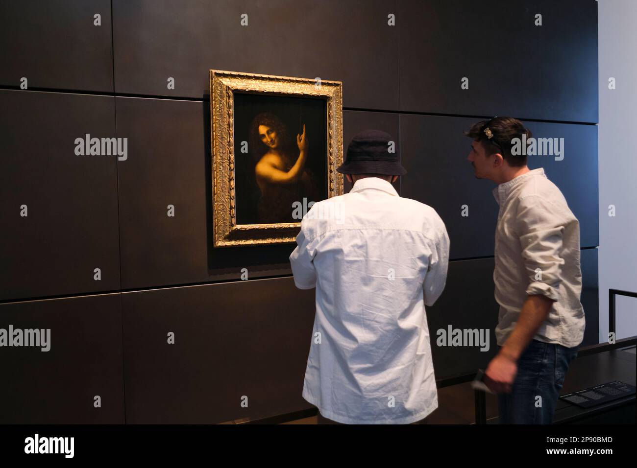 Persone che apprezzano il dipinto Giovanni Battista di Leonardo da Vinci. Al museo d'arte del Louvre francese ad Abu Dhabi, Emirati Arabi Uniti. Foto Stock