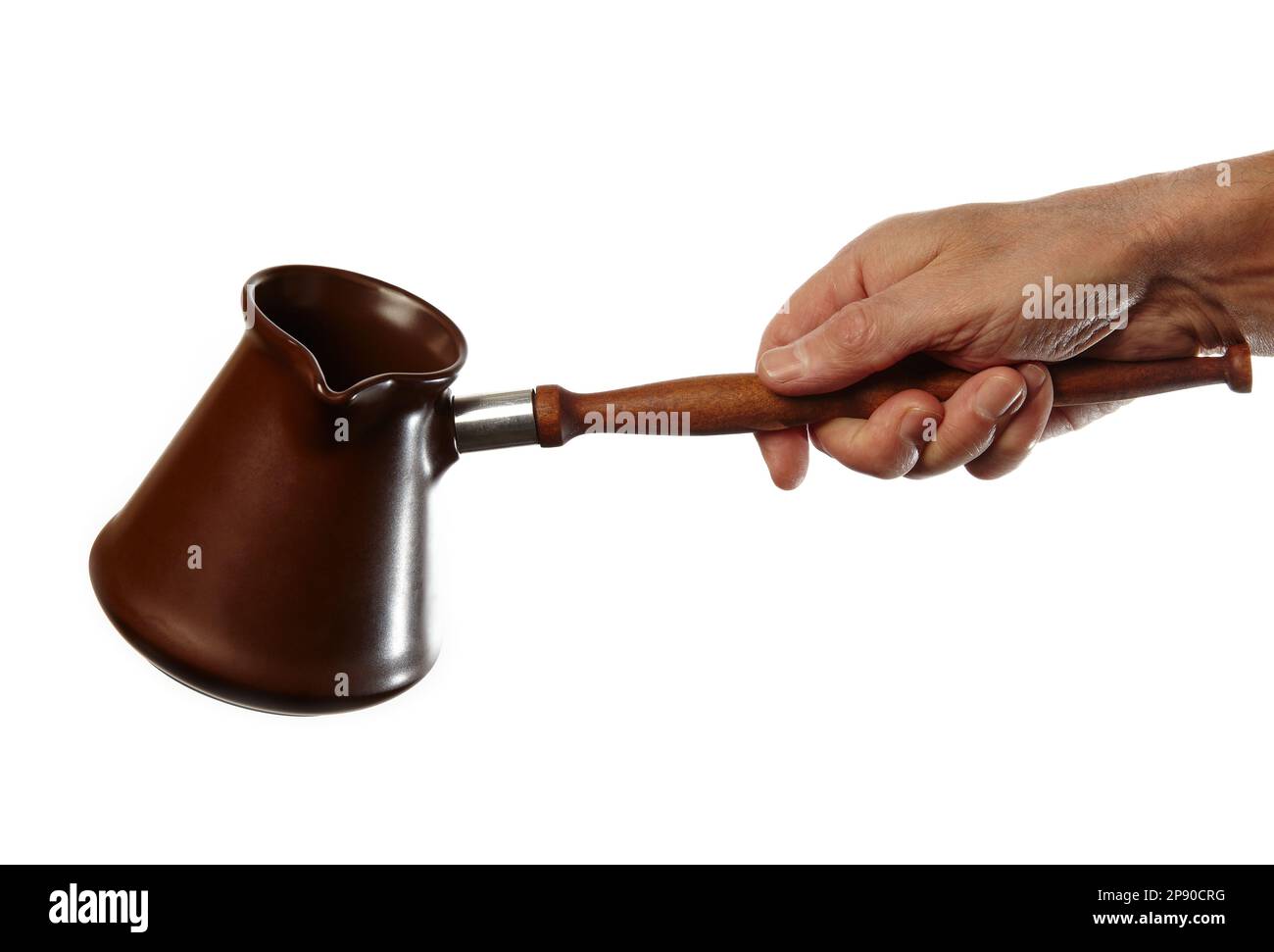 Mano da uomo che tiene il turk di caffè isolato sfondo bianco. Cezve di argilla per preparare il caffè in mano Foto Stock