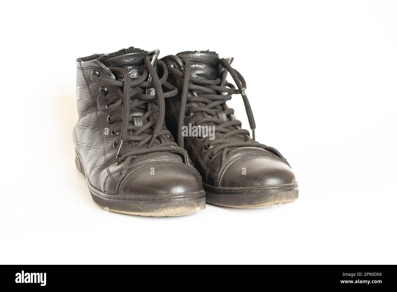 Scarpe da uomo in pelle nera sporche indossate su uno sfondo bianco da vicino Foto Stock