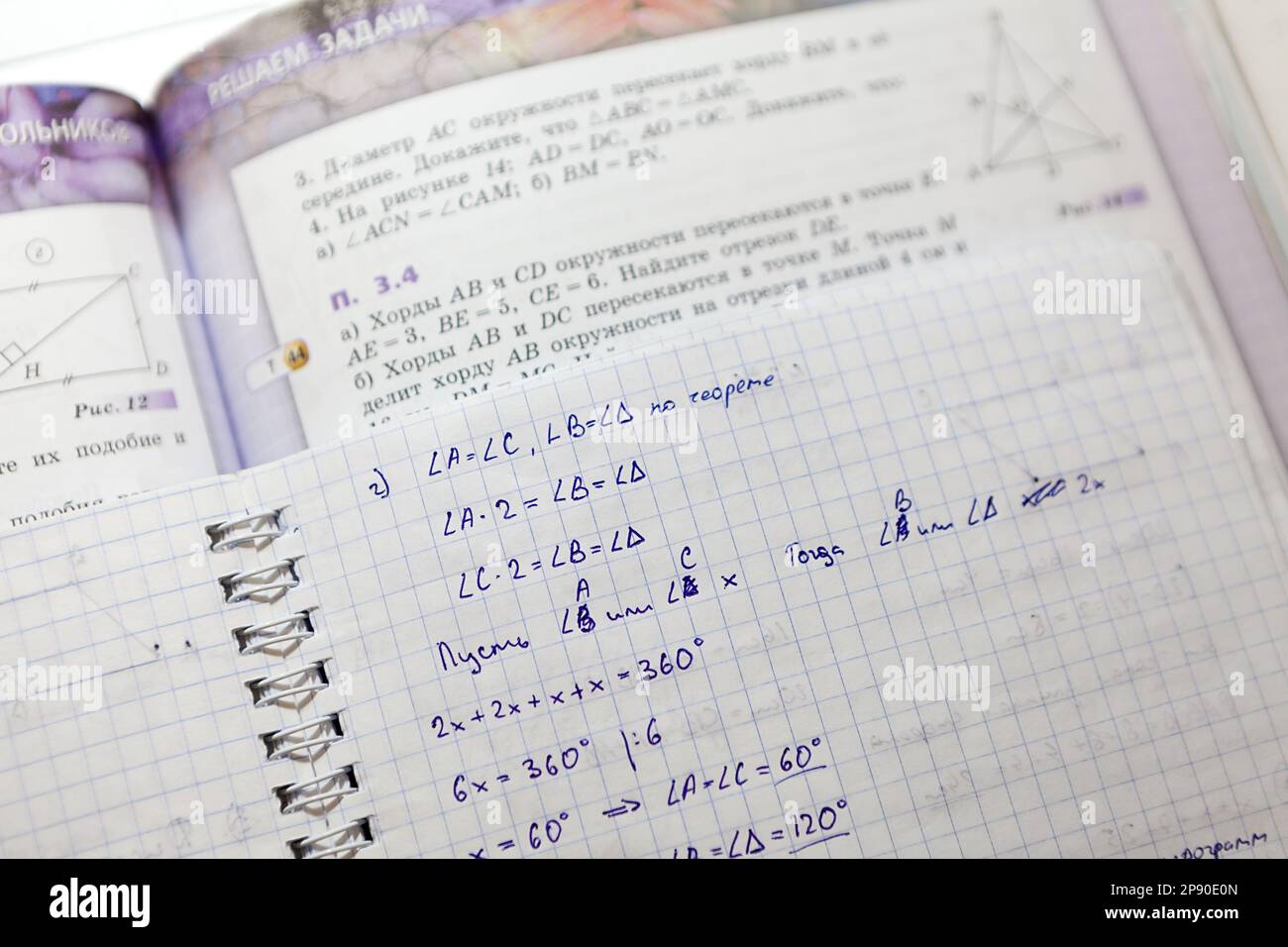 Un libro di testo con attività in geometria e un notebook scolastico con soluzioni Foto Stock