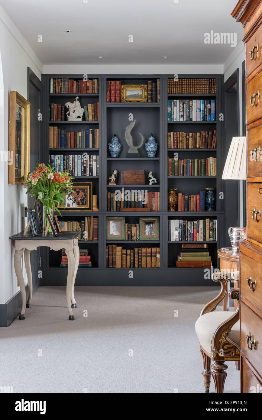 Scaffali di libri costruiti su misura con tallboy antico in casa Cotswolds di recente costruzione Foto Stock