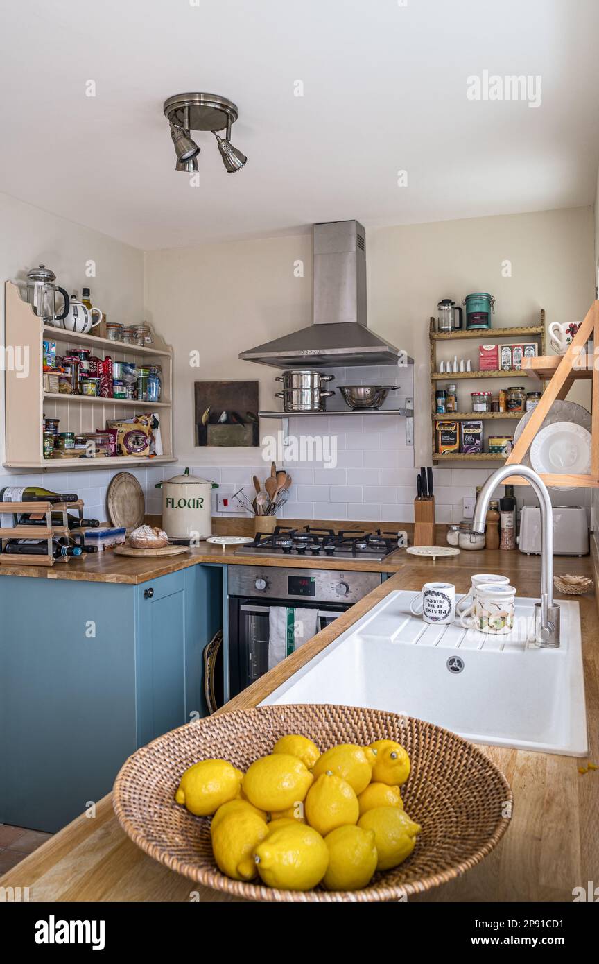 Ciotola di limoni e mensole a parete in cucina compatta ridisegnata con unità dipinte in 'Oval Room Blue', 19th ° secolo Norfolk cottage, Regno Unito Foto Stock