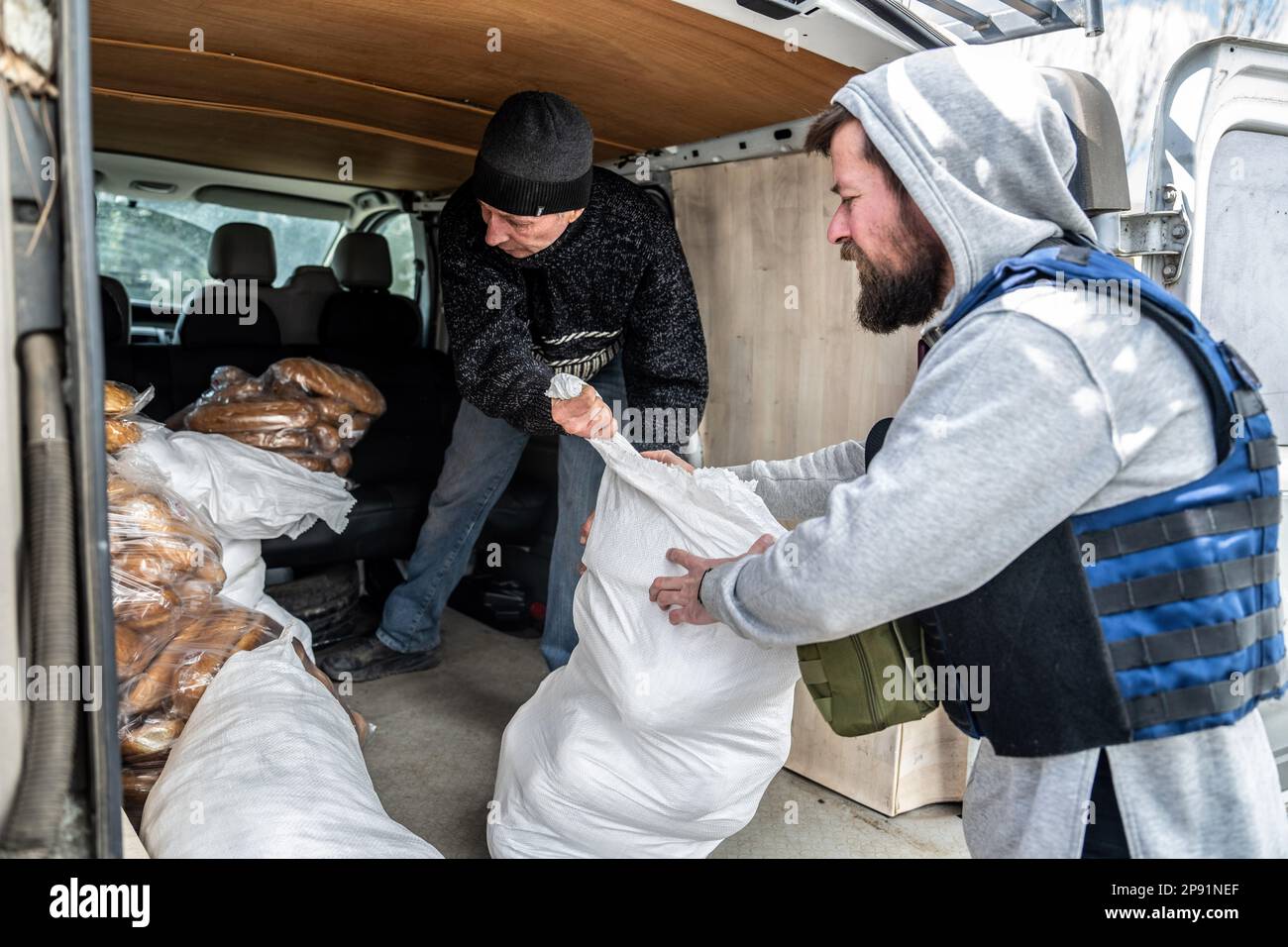 Volontari e residenti locali scaricano una consegna di pane fresco donato dalla ONG U-Saved a Chasiv Yar, una città sempre più sgusciata vicino alla città di Bakhmut in Donbas. Le forze russe e ucraine combattono da mesi per la città chiave di Bakhmut, oggi quasi interamente circondata dai russi. Foto Stock