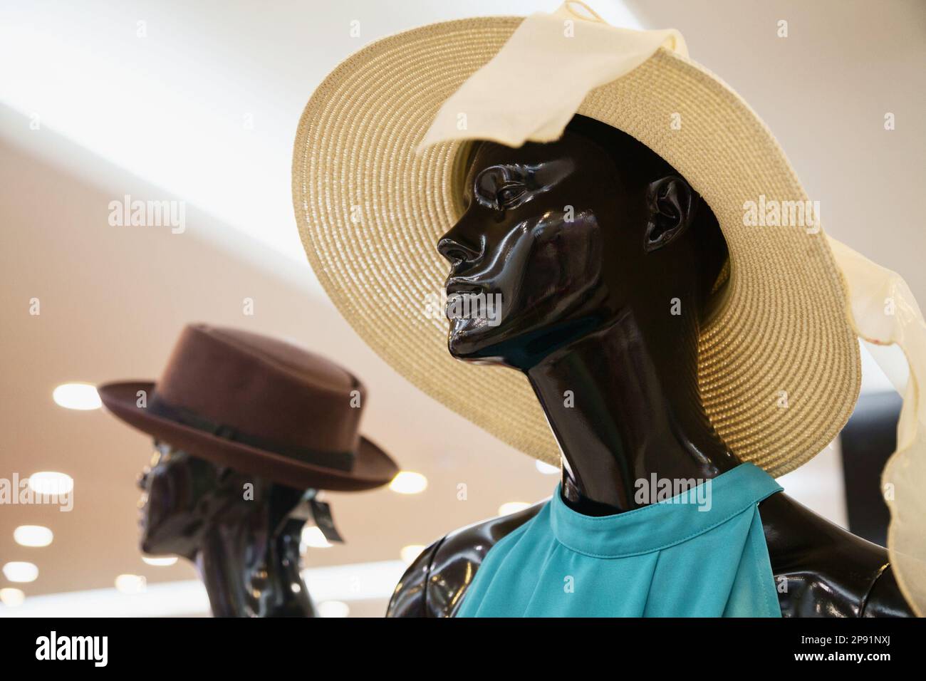 Triste Manichino donna che indossa un cappello di paglia in una finestra del negozio. Malinconici Manichino donna presenta estate moda stile in un negozio di abbigliamento Foto Stock