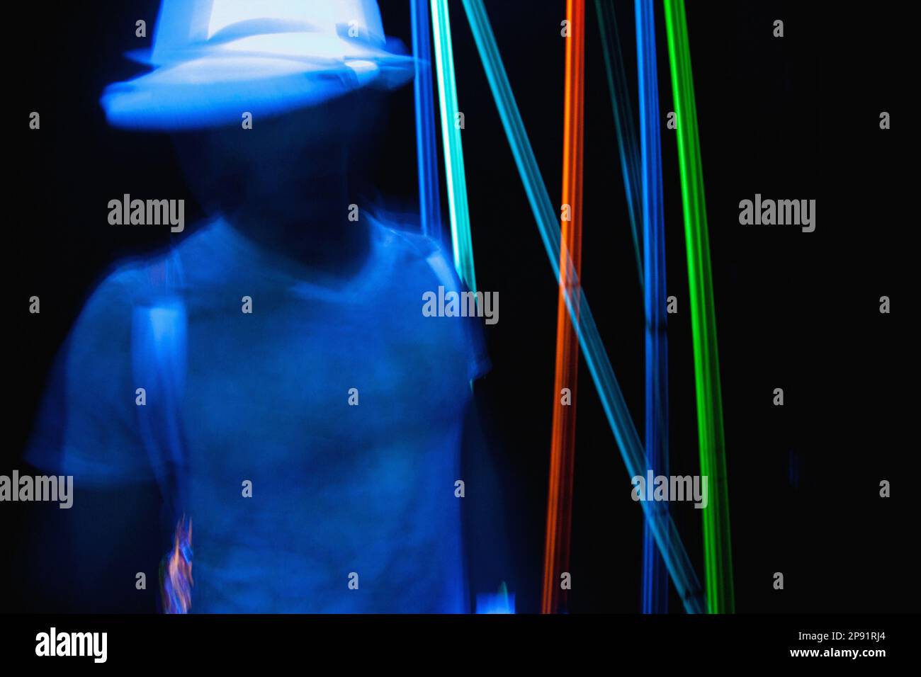 Uomo che balla al neon in un night club. Persona in movimento sfocata in discoteca luci sul nero Foto Stock