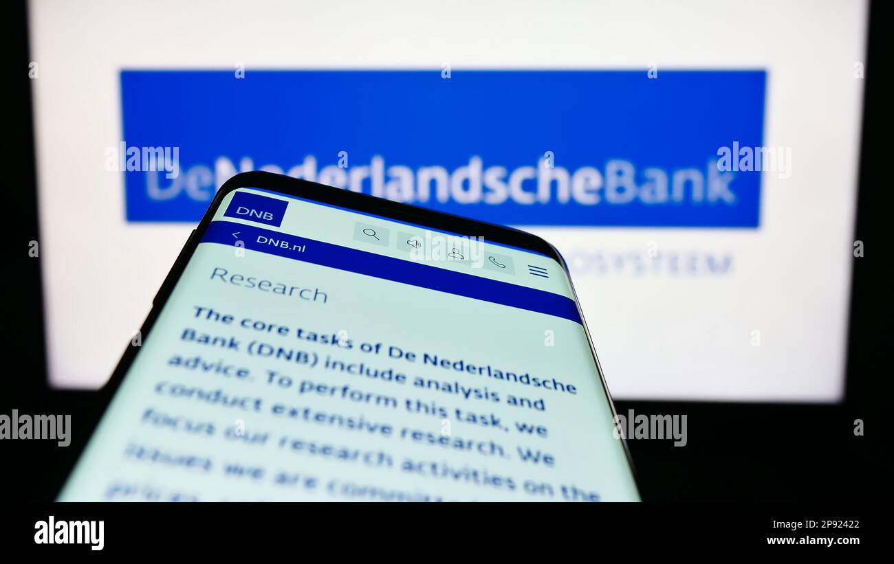 Telefono cellulare con pagina web della banca centrale olandese De Nederlandsche Bank (DNB) sullo schermo di fronte al logo. Messa a fuoco in alto a sinistra del display del telefono. Foto Stock