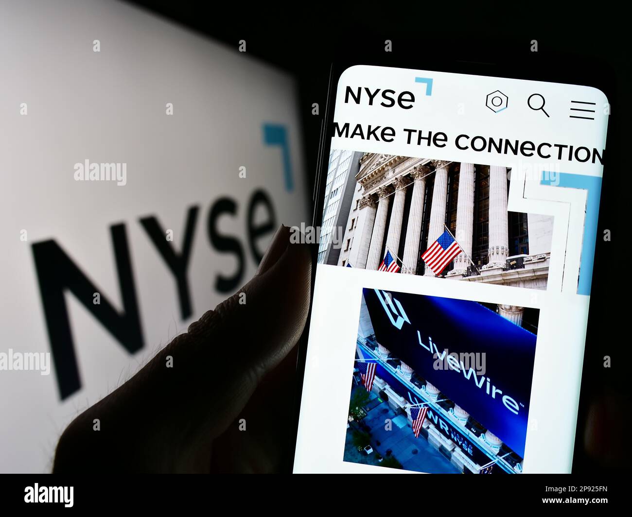 Persona che tiene il telefono mobile con il Web pageof mercato degli Stati Uniti New York Stock Exchange (NYSE) sullo schermo di fronte al logo. Messa a fuoco al centro del display del telefono. Foto Stock