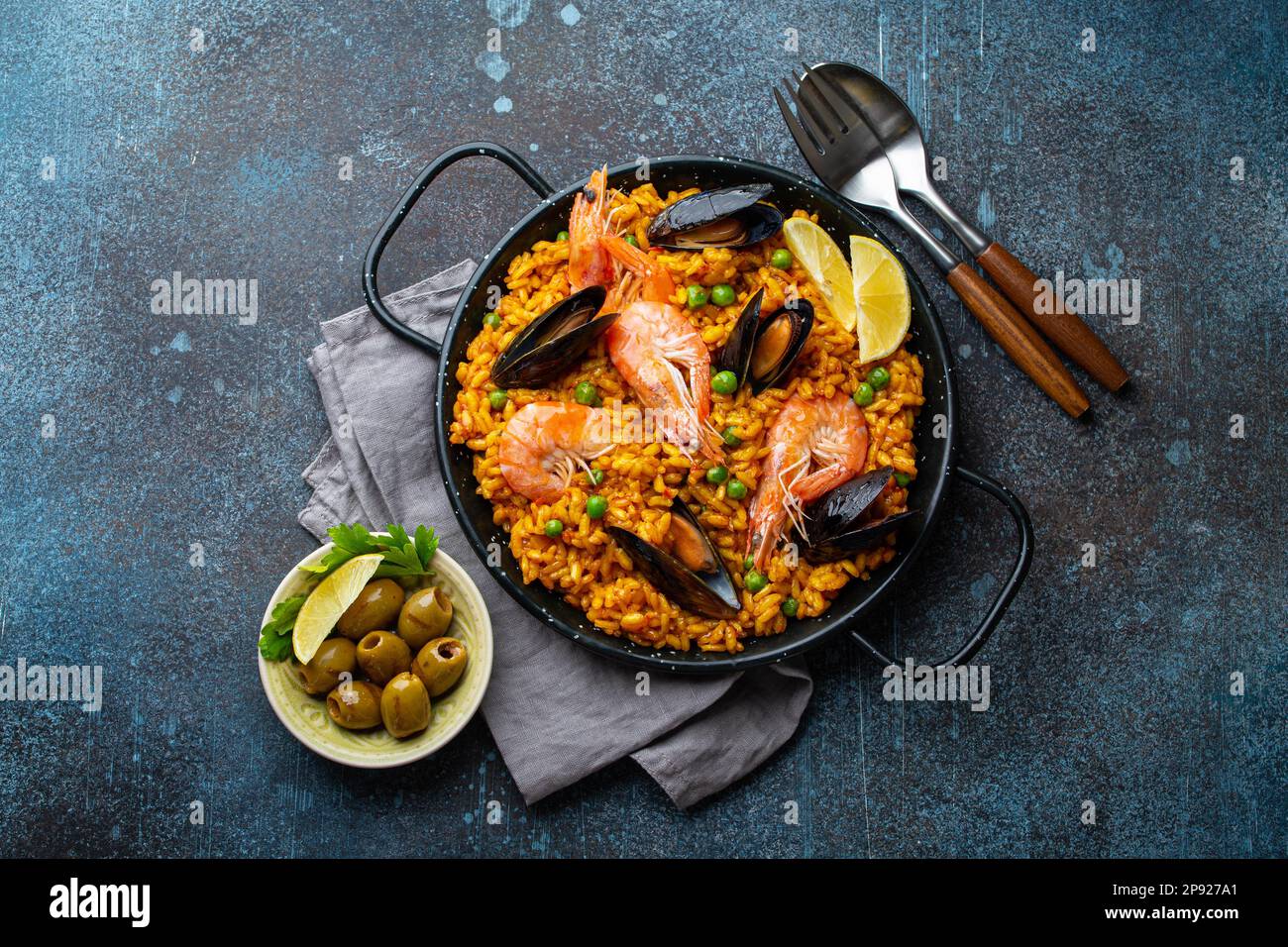 Piatto classico della Spagna, paella di pesce in padella tradizionale su sfondo rustico blu cemento vista dall'alto. Paella spagnola con gamberetti, pinze, cozze Foto Stock