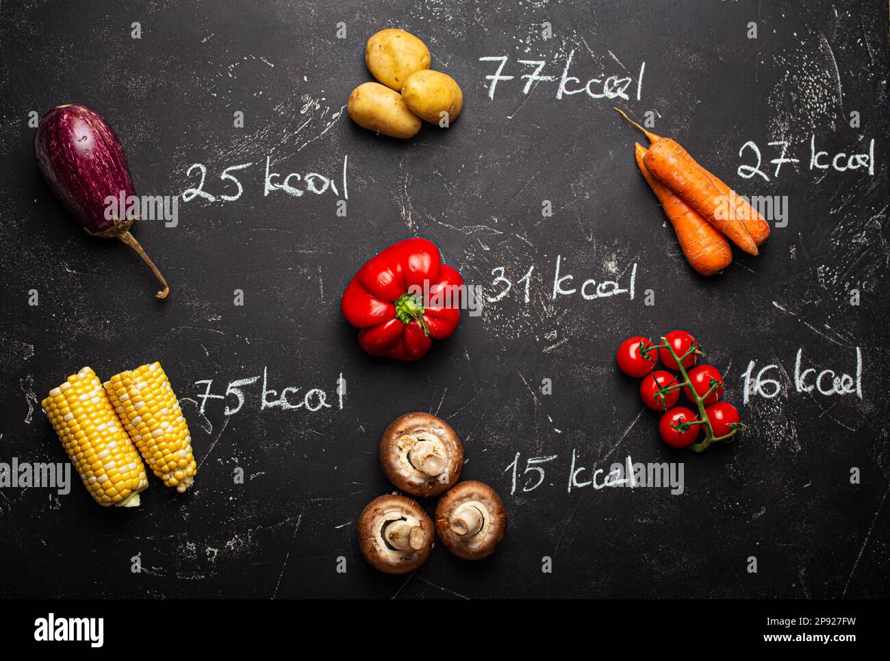 Vista dall'alto di diverse verdure su sfondo di pietra nera e gesso ha scritto quantità di calorie per la perdita di peso e il controllo degli alimenti. Dieta e calorie Foto Stock