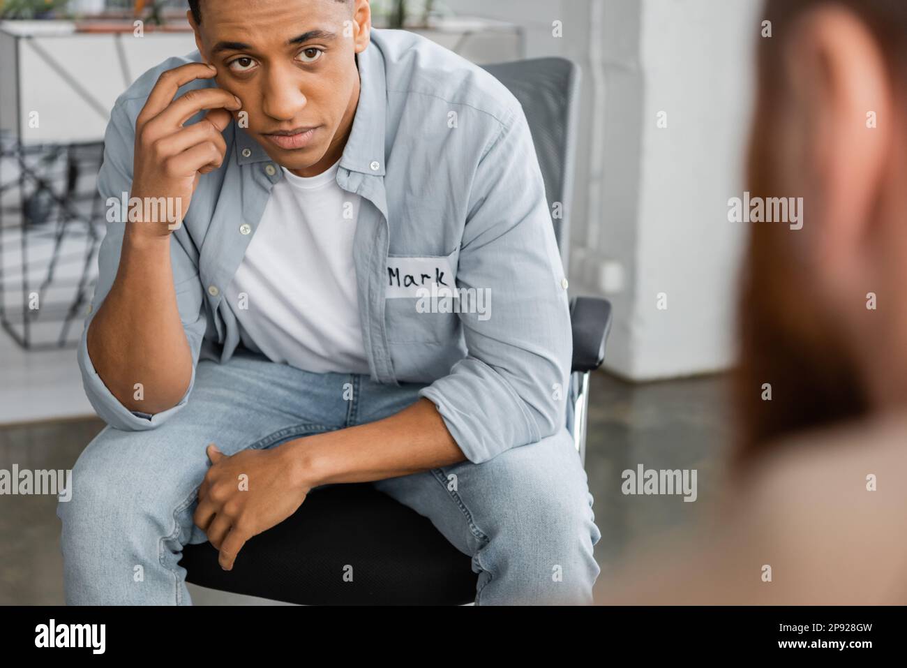 Uomo afroamericano sconvolto con dipendenza da alcol seduta a sessione di terapia di gruppo nel centro di riabilitazione, immagine stock Foto Stock