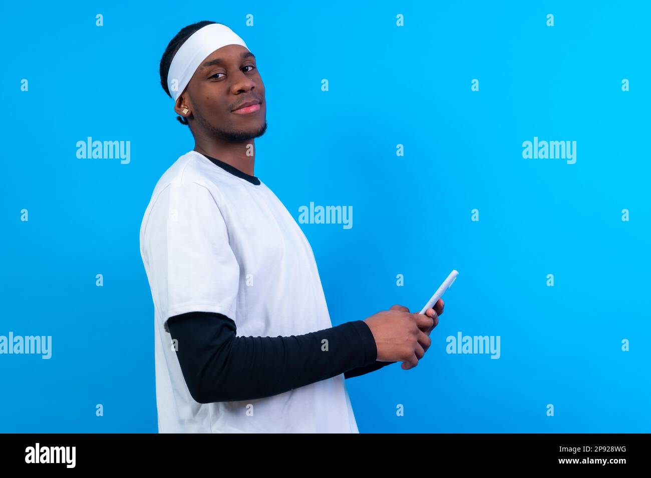 Uomo etnico nero con telefono in abiti bianchi su sfondo rosa Foto Stock