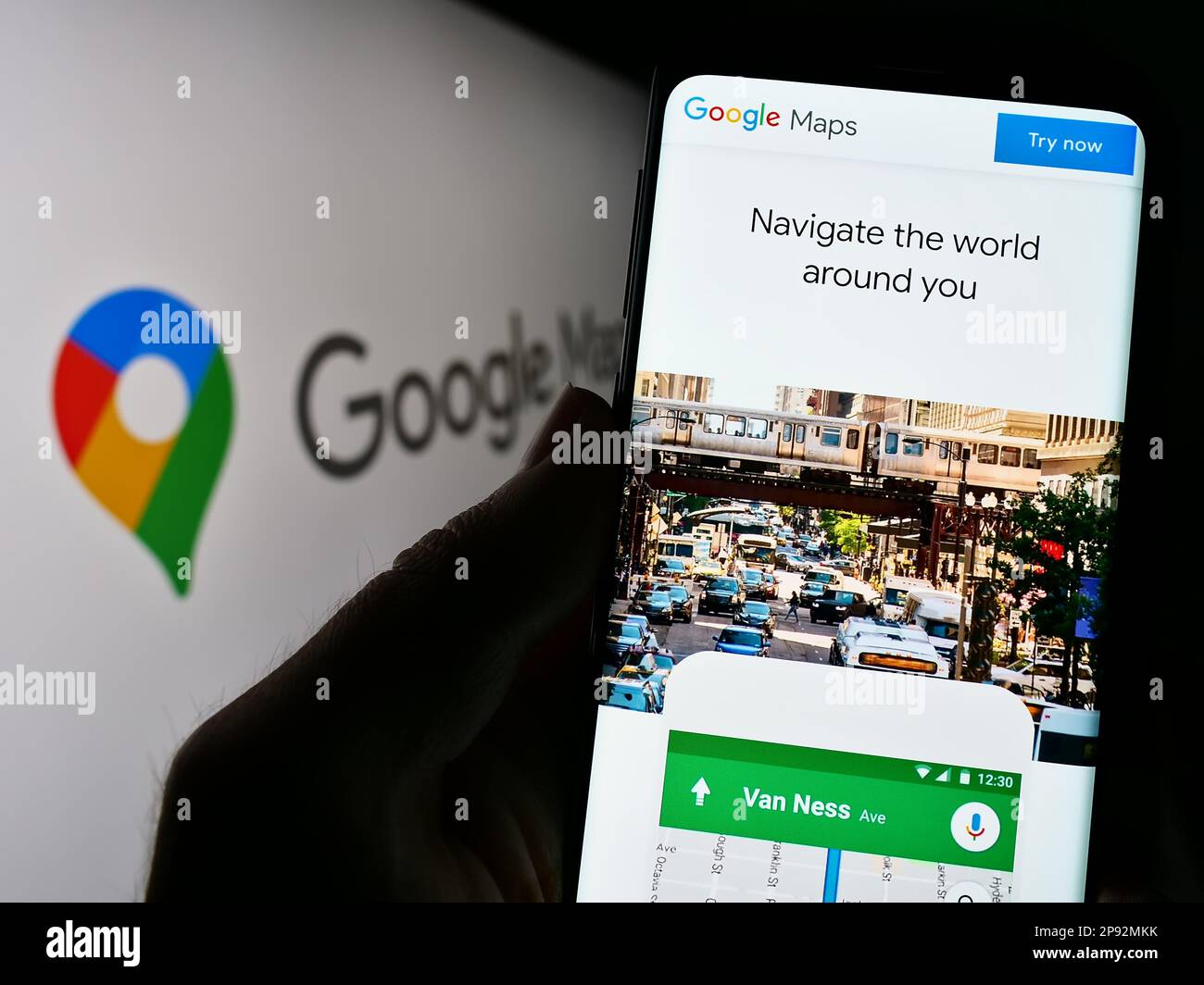 Persona che tiene il telefono cellulare con pagina web della piattaforma di mappatura web Google Maps sullo schermo di fronte al logo. Messa a fuoco al centro del display del telefono. Foto Stock
