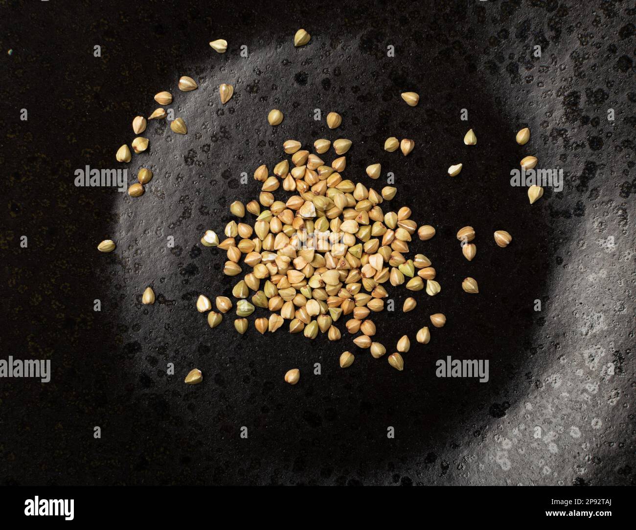 Semi crudi di grano saraceno verde su piastra nera isolata, grani di grano saraceno secco buck, Russian Kasha Heap, crudo grano saraceno verde vista dall'alto Foto Stock