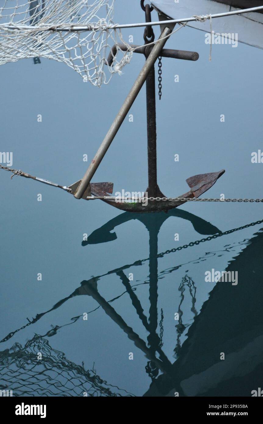 Vecchia ancora in acqua al mattino. Ancoraggio riflesso sopra la superficie dell'acqua. Foto Stock