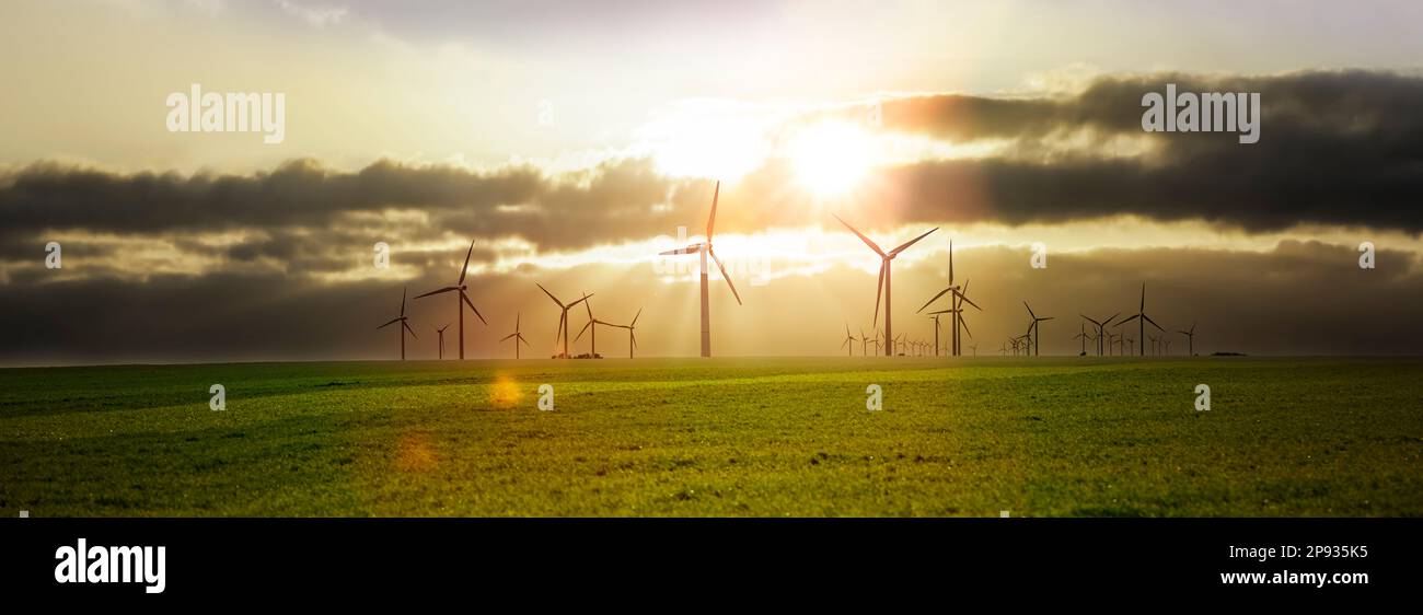 Turbine eoliche in un paesaggio con raggi solari Foto Stock