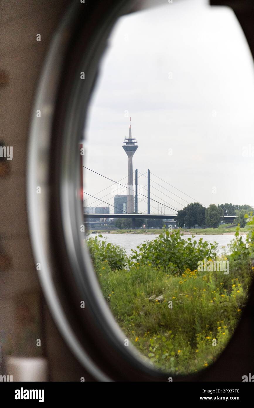 Vista attraverso un oblò di una nave del Reno fino alla torre della televisione di Düsseldorf e un ponte sul Reno Foto Stock