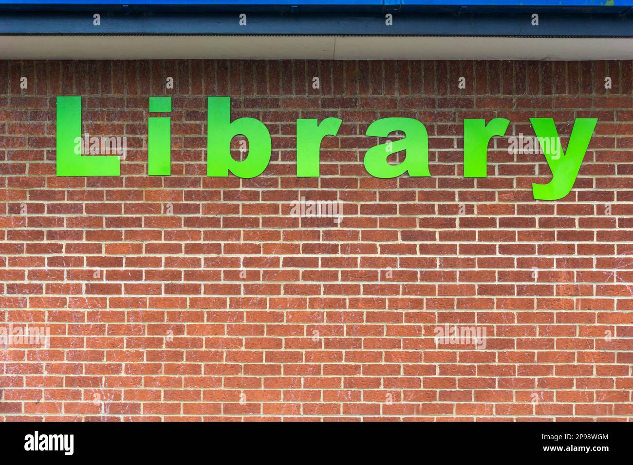 La parola Biblioteca in grandi lettere verdi sul muro di mattoni di una biblioteca pubblica. Foto Stock