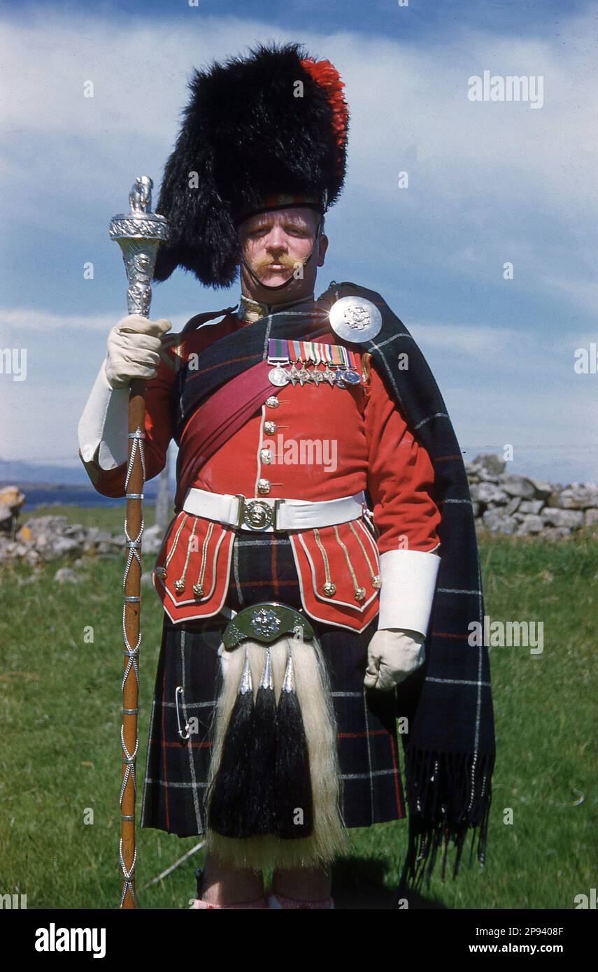 1960s, storico, un grande tamburo Highland nella sua uniforme e con macis cerimoniale, in piedi per la sua foto, Highland, Scozia, Regno Unito. Foto Stock