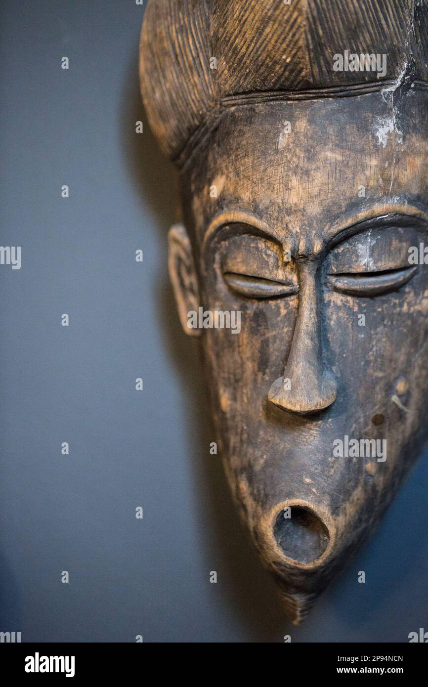 La maschera etnica è appesa a una parete scura Foto Stock