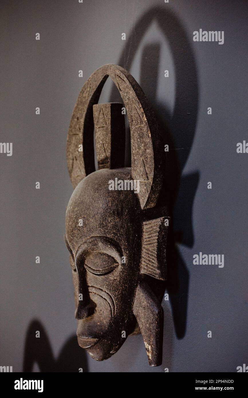 La maschera etnica è appesa a una parete scura Foto Stock