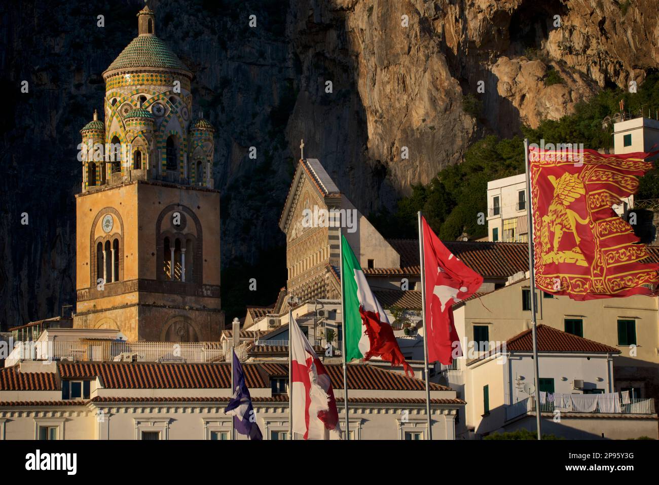 Bandiere sul molo e sul Campanile del Duomo di Sant'Andrea. Amalfi, Salerno, Italia Costiera Amalfitana. Iniziata nei secoli 9th e 10th, la cattedrale è stata aggiunta e ridecorata più volte, sovrapponendo elementi arabo-normanni, gotici, rinascimentali, barocchi, E infine una nuova facciata Normanno-Arabo-Bizantina del 19th° secolo. Bandiere multiple sui flagpoli che soffiano nel vento Foto Stock